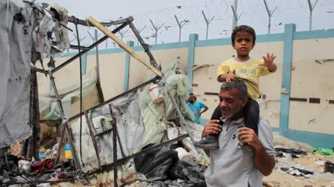 Reuters A man and a young boy walk among ruins in Rafah