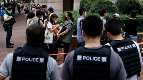 Reuters People queue up outside the West Kowloon Magistrates' Courts building, before the verdict of the 47 pro-democracy activists