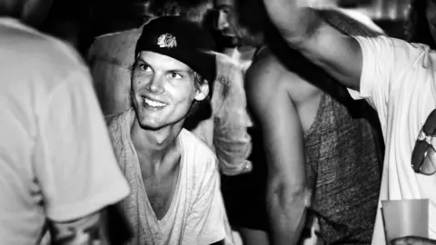 Cim Ek/Avicii Music AB Avicii surrounded by people, apparently in a nightclub