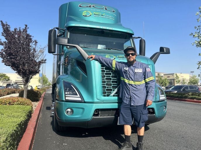 QCD driver standing in front of Volvo VNR Electric truck