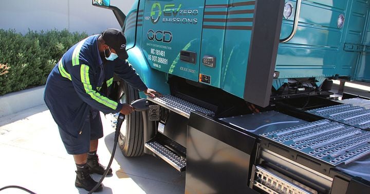 Truck driver plugging in electric charger for Volvo VNR Electric truck.