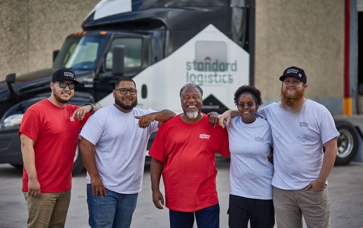 Group of diverse Standard Logistics truck drivers in front of truck