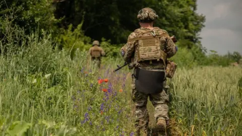 Getty Images A Ukrainian soldier walks through a field during a training exercise near Kyiv