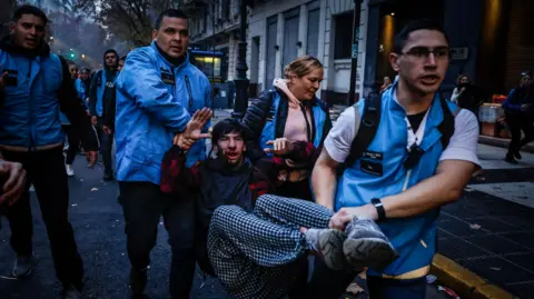 EPA A man receives help during clashes with police