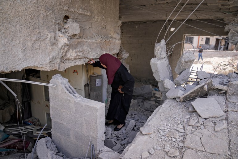 Palestinians look at the damage following an Israeli airstrike in the West Bank Jenin refugee camp, Saturday, May 18