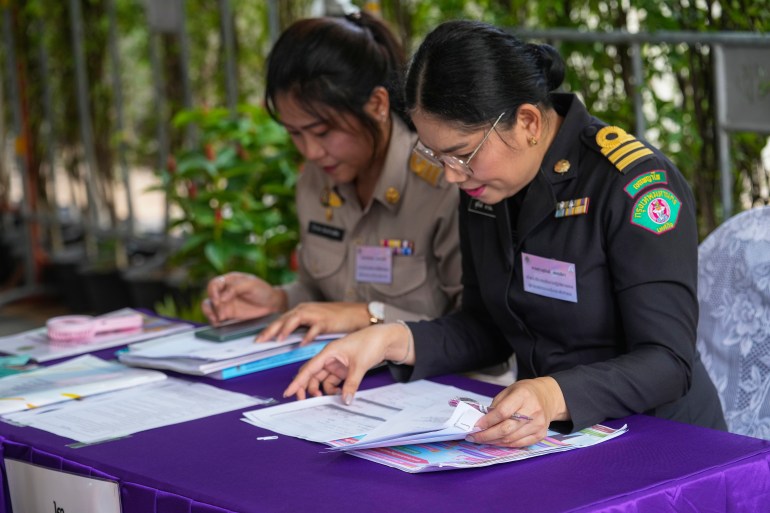 Two officials checking candidate papers for the Senate. Both are women. One is in a dark green uniform