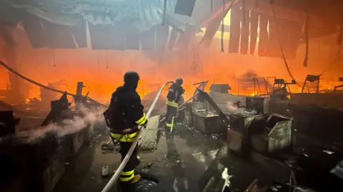 Reuters Firefighters work at a site of a household item shopping mall hit by a Russian air strike, amid Russia's attack on Ukraine, in Kharkiv, Ukraine