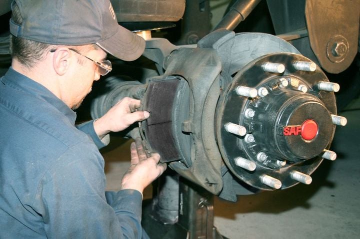 Technician working on truck air disc brakes.