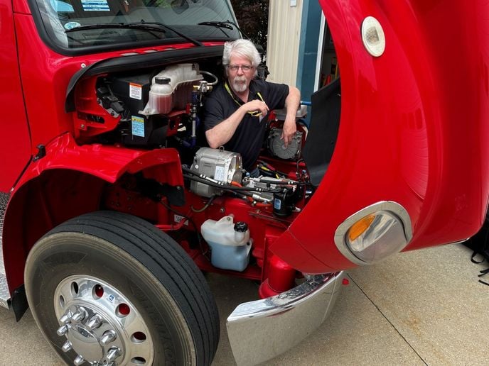 HDT equipment editor Jim Park in the engine bay of a Freightliner truck.