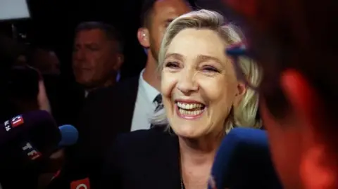 REUTERS/Yves Herman Marine Le Pen, French far-right leader and far-right Rassemblement National (National Rally - RN) party candidate, speaks to journalists after partial results in the first round of the early French parliamentary elections in Henin-Beaumont, France, June 30, 2024