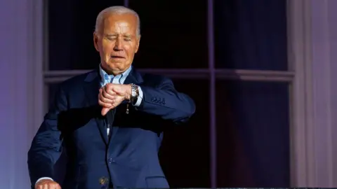 Getty Images Joe Biden checks his watch during Fourth of July celebrations at the White House