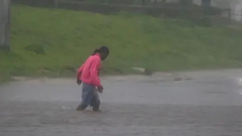 Reuters A man walks in a flooded street as Hurricane Beryl hits the southern coast of the island, in Kingston, Jamaica, July 3, 2024