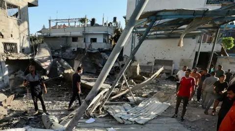 Reuters People walk through the ruins of a school that was hit by an airstrike, killing at least 16 people.