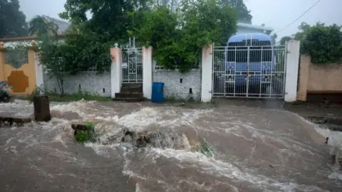 Getty Images Floodwater rages through street with buildings in the background