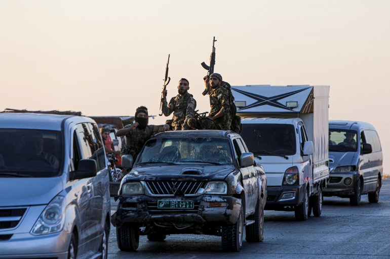 Armed men drive in the back of a pick up truck during protests against Turkey in al-Bab, in the northern Syrian opposition held region of Aleppo on July 1, 2024. - A man was killed after and Turkish forces clashed in Syria's Ankara-controlled northwest, a war monitor said, in demonstrations sparked by violence against Syrians in Turkey a day earlier. (Photo by Bakr ALKASEM / AFP)