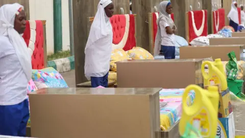 AFP Household items given to couples are seen beside brides at the venue of a wedding reception at the Kano state governor's office after taking part in a mass wedding at the central mosque in Kano city, Nigeria - October 2023