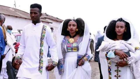 Cassette Biniam and his wife, Saliem, hold hands as his their baby daughter is carried beside them