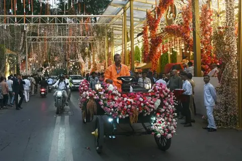 Reuters A decorated vehicle rides past Chairman of Reliance Industries Mukesh Ambani's residence Antilia in Mumbai on July 3, 2024