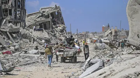 EPA Displaced Palestinians walk through rubble in Gaza