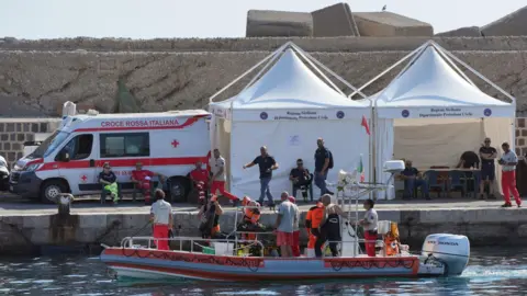 PA Media An Italian fire service dive team return to port on the fifth day of the search and recovery operation