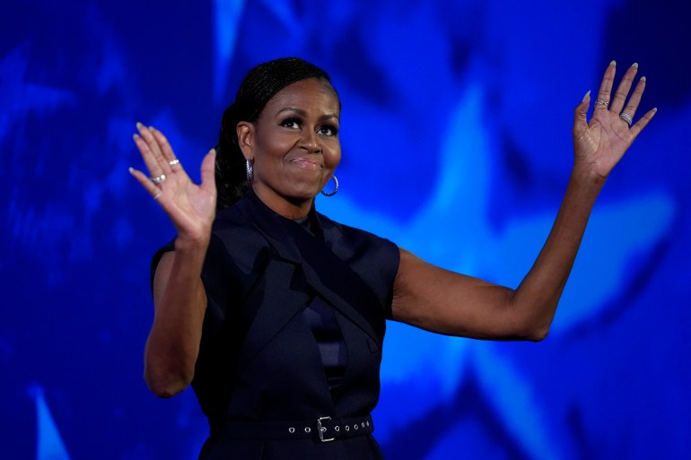 Michelle Obama acknowledges the crowd. He is smiling.