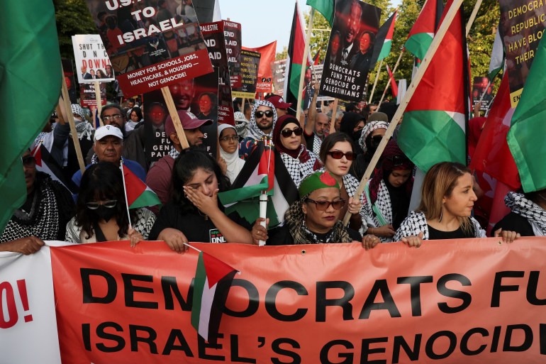 a woman cries as people hold a banner saying democrats fund Israel's genocide