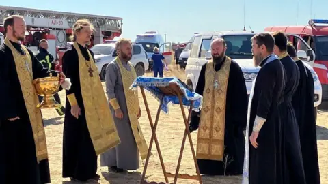 Reuters Russian Orthodox clergymen conduct a service around the Unburnt Bush icon, which is considered by Christians in Russia as a talisman against fire, near the accident site at the Proletarsk fuel depot that caught fire following a reported Ukraine's drone attack in the course of Ukraine-Russia conflict, in the Rostov region