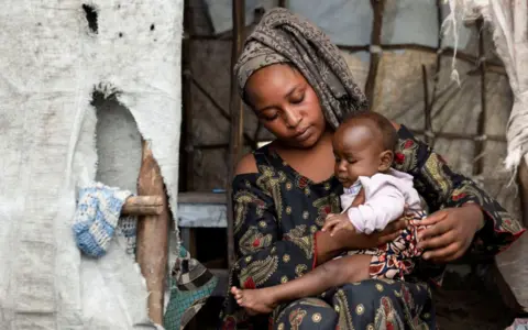 ARLETTE BASHIZI / REUTERS Justine Munguiko holds her child who has been cured of Mpox.