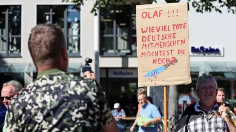 Reuters People attend a protest following a stabbing rampage in Solingen in which several individuals were killed and injured, as German Chancellor Olaf Scholz visits a Social Democratic Party (SPD) election campaign rally, in Jena, Germany, August 27, 2024.