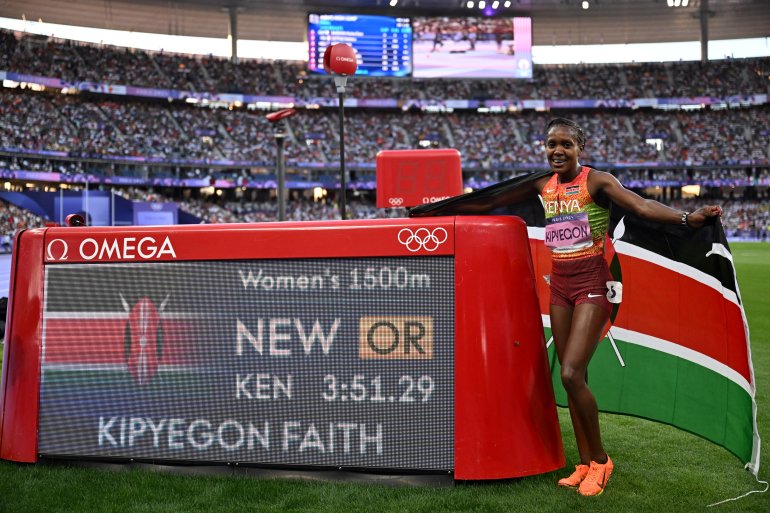 Gold medallist Kenya's Faith Kipyegon poses by the score board after setting a new Olympic record in the women's 1500m final of the athletics event at the Paris 2024 Olympic Games at Stade de France in Saint-Denis, north of Paris, on August 10, 2024. (Photo by Kirill KUDRYAVTSEV / AFP)