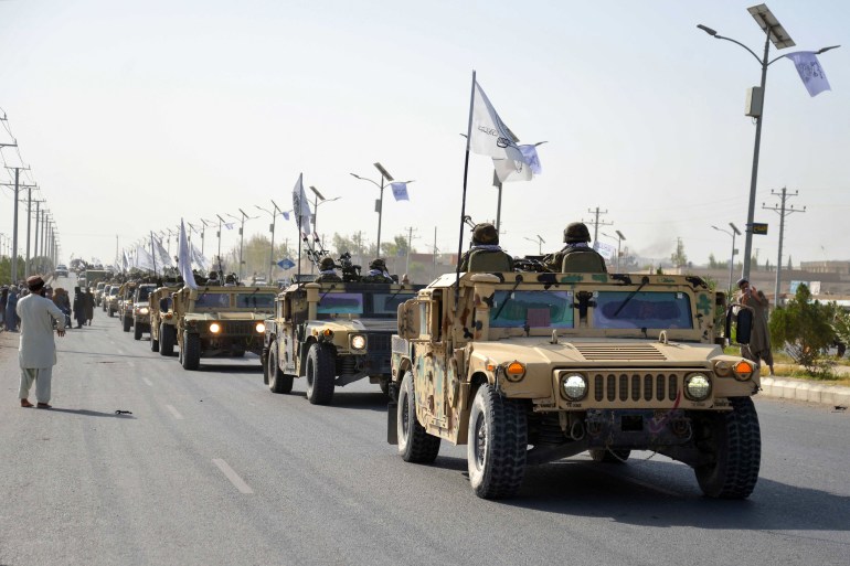 Taliban security personnel of Afghanistan military's 205 Al-Badr Corps carrying Taliban flags, parade to celebrate the third anniversary of Taliban's takeover of the country, in Kandahar on August 14, 2024. - Taliban authorities kicked off celebrations of the third anniversary of their rule over Afghanistan on August 14, at the former US Bagram air base. (Photo by Sanaullah SEIAM / AFP)