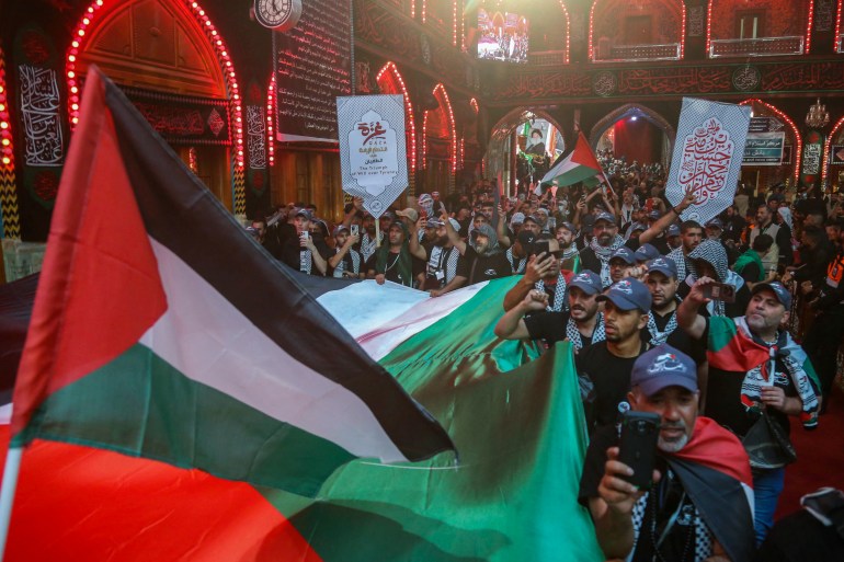 Devotees lift flags of Palestine and wear traditional Palestinian keffiyeh scarves to express support for Gaza, as they take part in a mourning ritual at the shrine of Imam Abu Al-Fadl al-Abbas in Iraq's Karbala on August 24, 2024, as Shiite Muslim pilgrims gather in the holy shrine city for the Arbaeen commemorations that mark the end of the 40-day mourning period for the seventh century killing of the Prophet Mohamed's grandson Imam Hussein Bin Ali. (Photo by Mohammed SAWAF / AFP)