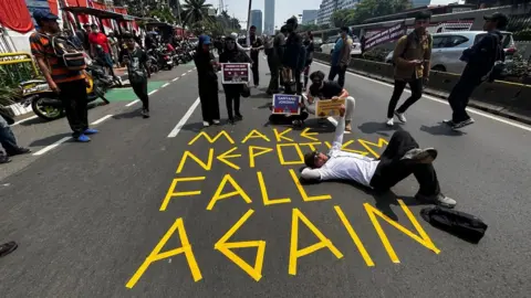 Anindita Pradana/BBC Indonesia Protesters in front of sign on the road which says: "Make nepotism fall again".