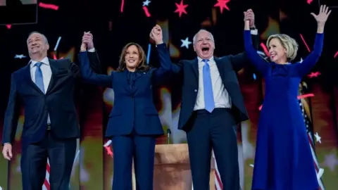 EPA Doug Emhoff, Kamala Harris, Tim Walz and Gwen Walz hold hands at the Democratic National Convention