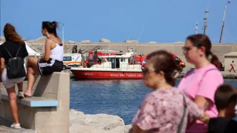 Reuters People watch rescue team near yacht sinking site