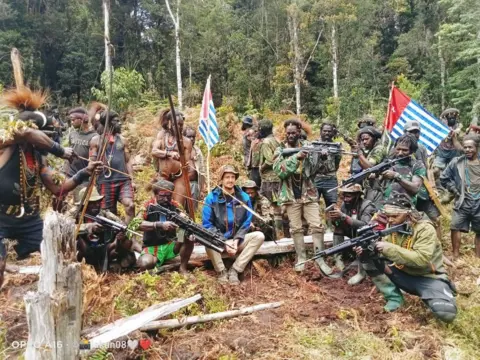 Reuters Philip Mehrtens sits between armed separatist fighters in Indonesia's Papua region.