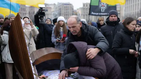 Getty Images Ukrainians cry at a funeral in Kyiv, January 2024