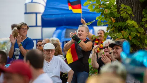 Getty Images Woman cheers at rally with German flag