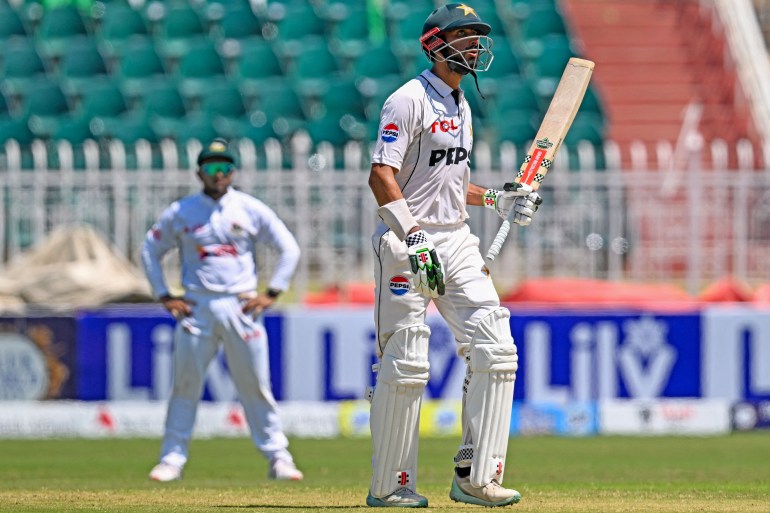 Pakistan's captain Shan Masood (R) celebrates after scoring a half-century (50 runs) during the second day of second and last cricket Test match between Pakistan and Bangladesh, at the Rawalpindi Cricket Stadium in Rawalpindi on August 31, 2024. - Bangladesh won the toss and sent Pakistan in to bat in the second Test on August 31 after the first day's washout Friday due to rain in Rawalpindi. (Photo by Aamir QURESHI / AFP)