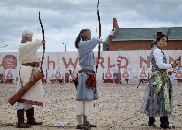 Three archers competing in the Nomad Games. They sre wearing traditional clothing. One is looking at the camera.