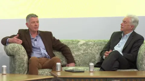 FT Sir Richard Moore, MI6 chief, wearing a brown suit, sits on a green patterned sofa with William Burns, head of the CIA, who is wearing a dark suit and has has hands clasped.