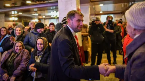 Getty Images Ilan Shor - pictured here while running for election in 2019 - is seen shaking a woman's hand