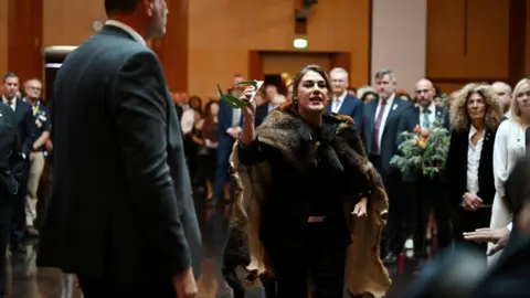 Reuters Thorpe wearing a possum skin cloak gesticulates as she stands amongst a crowd of people