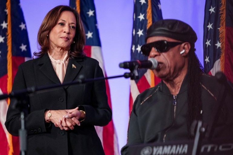 Kamala Harris looks on as Stevie Wonder sings