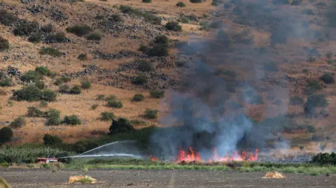 EPA Firefighters douse a fire that broke out as a result of projectiles fired from southern Lebanon, near Kfar Szold in northern Israel, 11 October 2024