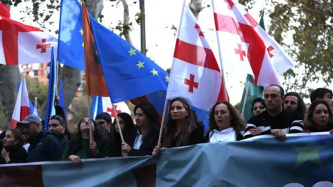 Getty Images Thousands of people, waving European Union (EU), Georgian and Ukrainian flags take part in a rally on 20 October in Tbilisi