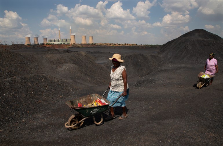 A woman pushes a wheel barrow in a coal mine dump on an afternoon in a power station in Johannesburg