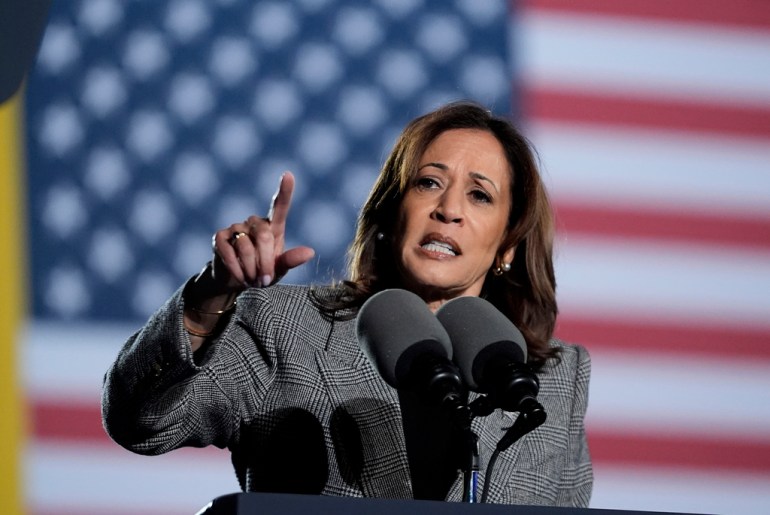 a woman speaks in front of a US flag