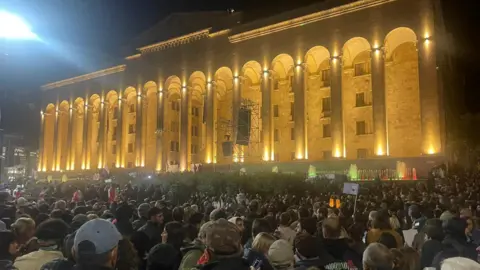 A crowd in front of an illuminated building