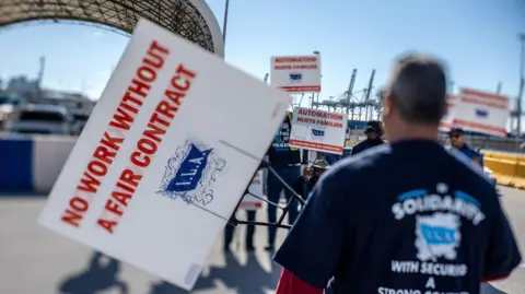 EPA-EFE Dockworkers attend a demonstration and hold signs up at the Port of Miami on the first day of the East and Gulf Coast cargo facilities dockworkers strike in Miami, Florida, USA, 01 October 2024. 